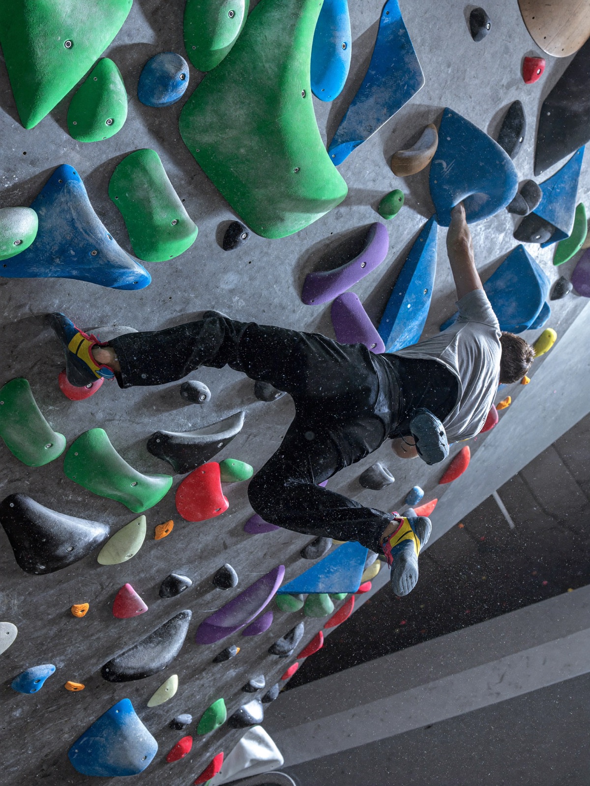 Climber reaching across an overhanging wall covered in colorful holds